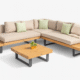 Modern Nevada sectional sofa with teak wood platform, black metal legs, integrated wooden tables, and beige outdoor cushions — styled in a contemporary patio setting.